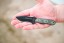 TOPS Desert Son compact fixed blade knife featuring a black recurve blade with jimping and a layered, light-toned ergonomic Black Linen Micarta handle.